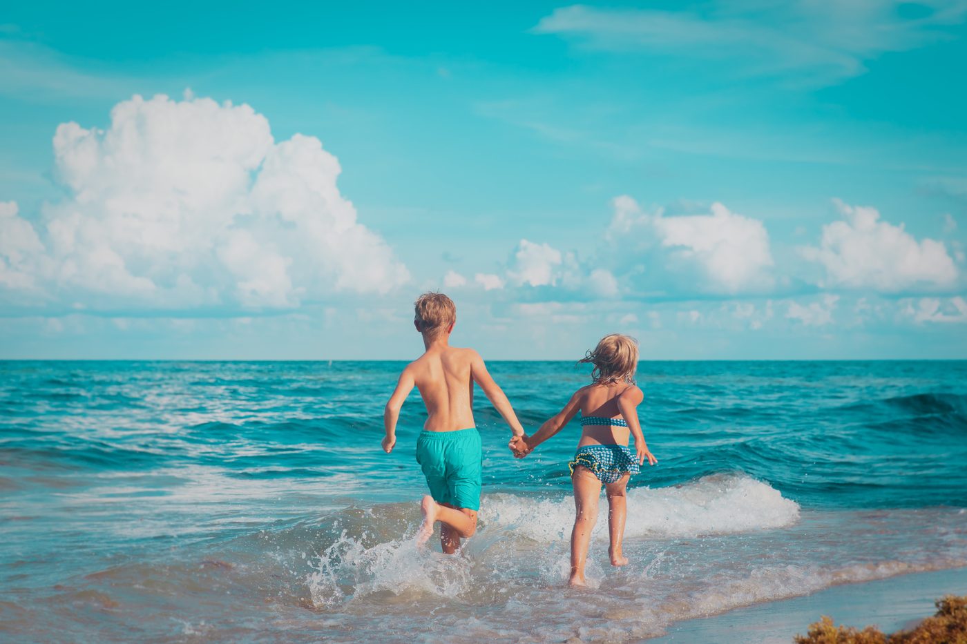 Two children running into the ocean