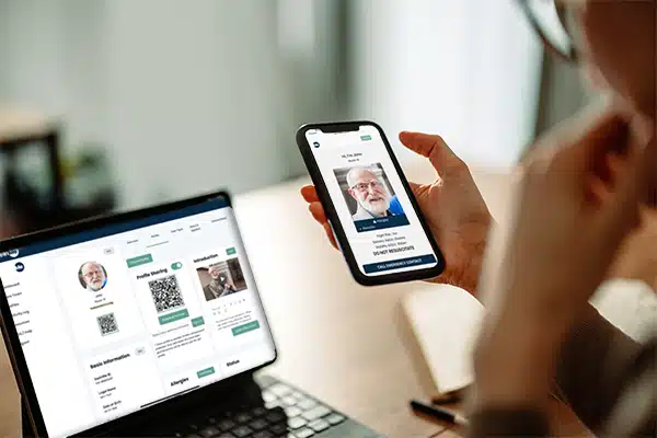 Woman looking at a shared profile on her phone with the management platform in on her iPad in the background