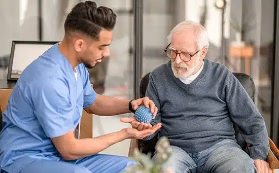 Focused rehabilitation physician massaging the palm of an elderly patient with a spiky massage ball